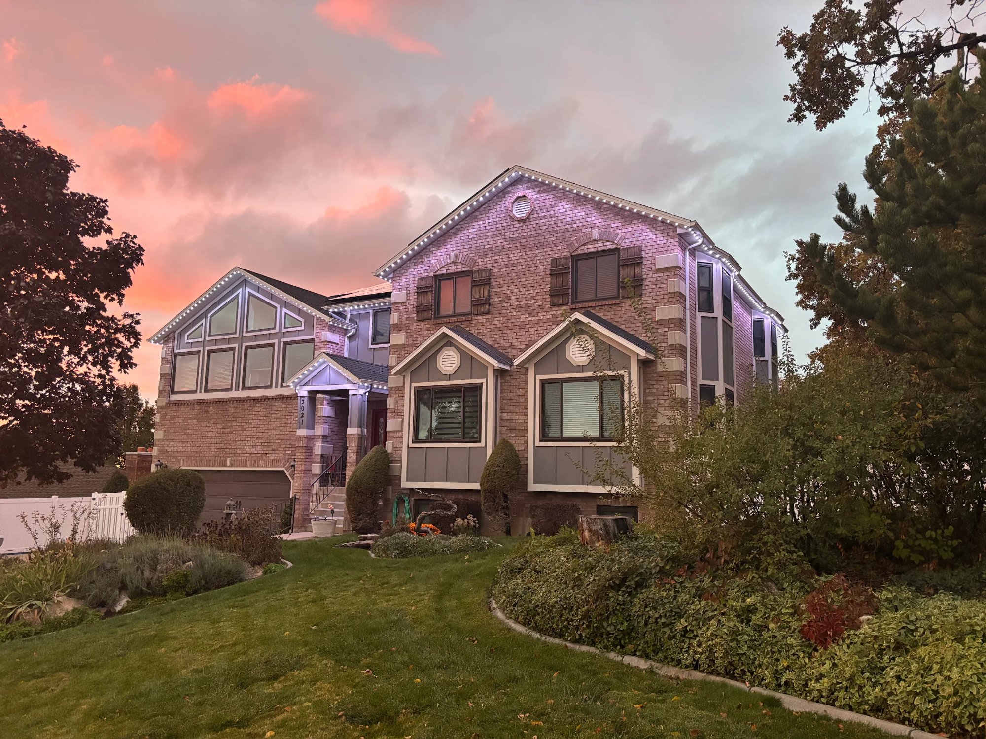 Brick home at sunset with warm white and violet roofline LEDs